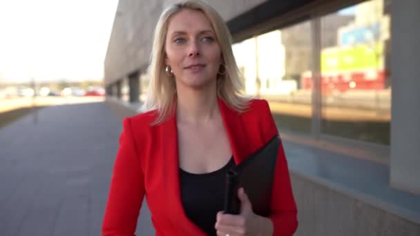 Bizneswoman w średnim wieku stojąca przed budynkiem biurowym. — Wideo stockowe