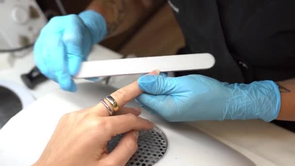 Esthéticienne faisant la manucure, classant les ongles avec une lime à son client dans un centre de beauté — Video