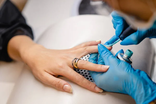 Крупним планом косметолог малює своїм клієнтам цвяхи в синьо-жовтому лаку для нігтів . — стокове фото