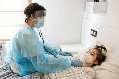 Doktor evde steteskoplu küçük bir kızı muayene ediyor..