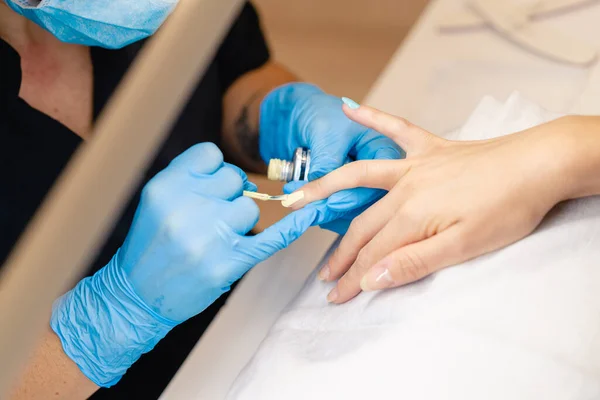 Крупним планом косметолог малює своїм клієнтам цвяхи в синьо-жовтому лаку для нігтів . — стокове фото