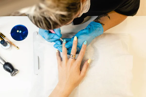 Close-up of Beautician painting her clients nails in blue and yellow nail varnish. — Stock Photo, Image