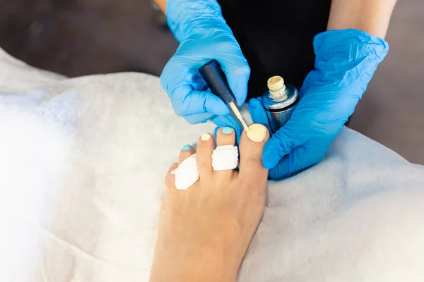 Esteticista dando um pedicuro pintando seus clientes unhas em um centro de beleza. — Fotografia de Stock