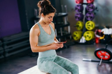 Woman consulting her training on her smartphone sitting in a jump box