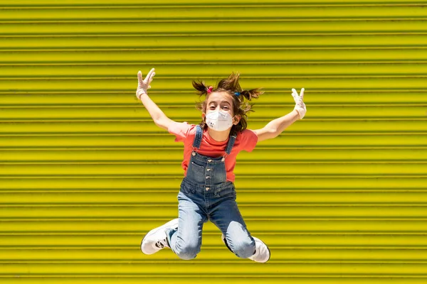 Девочка прыгает в защитной маске против коронавируса — стоковое фото