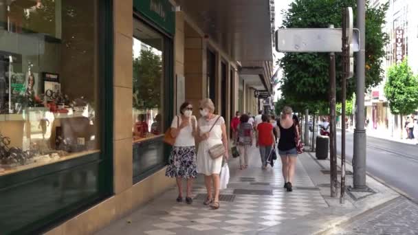 Ludzie idący ulicą handlową w maskach. — Wideo stockowe