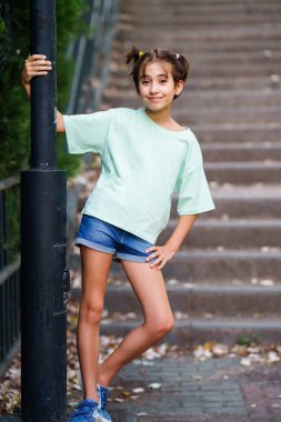 9 yaşında bir kız merdivenlerde dikiliyor.