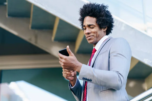 Black Businessman använder en smartphone nära en kontorsbyggnad — Stockfoto