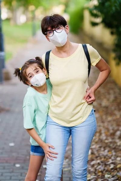 Madre e figlia di mezza età in piedi sulla strada indossando maschere — Foto Stock
