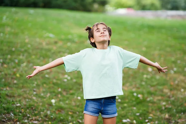 Menina de nove anos respirando com os braços abertos na grama — Fotografia de Stock