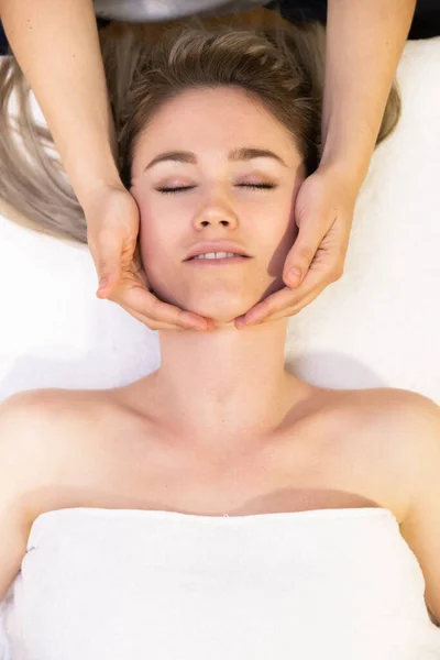 Jovem loira recebendo uma massagem na cabeça em um centro de spa . — Fotografia de Stock