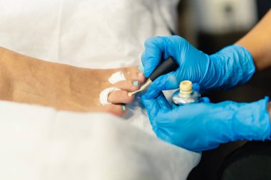 Güzellik uzmanı müşterilerine güzellik merkezinde tırnaklarını boyuyor..