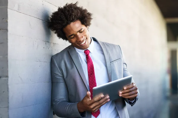 Zwarte zakenman met behulp van een digitale tablet in stedelijke achtergrond — Stockfoto