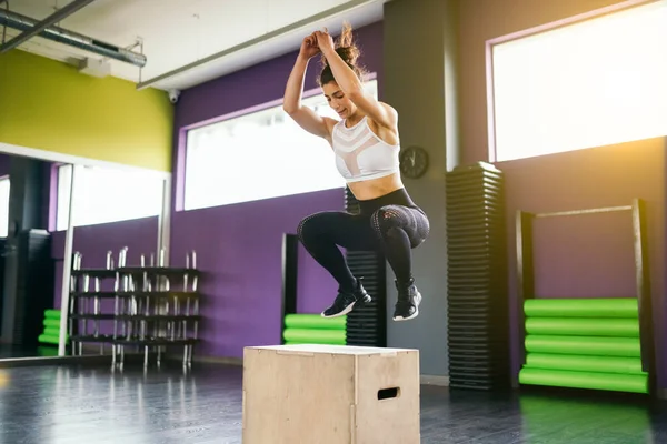 Fitness woman jumping onto a box as part of exercise routine. — Stock Photo, Image