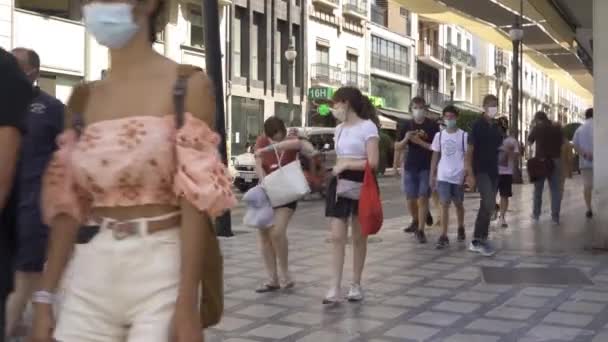 Mensen lopen door een commerciële straat met maskers op. — Stockvideo