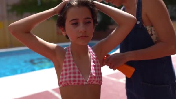 Mor sätter solkräm på sina små flickor axlar — Stockvideo