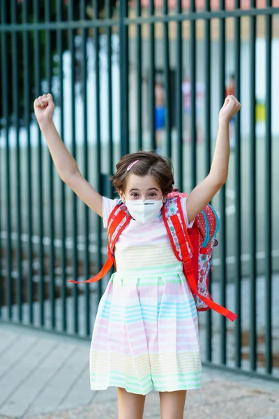 Девушка в маске прыгает от радости от возвращения в школу. — стоковое фото