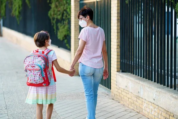 Nove anos de idade menina com saco andando com a mãe na mão . — Fotografia de Stock