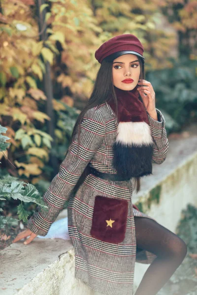 Joven hermosa chica con el pelo muy largo con abrigo de invierno y gorra en el fondo de las hojas de otoño —  Fotos de Stock