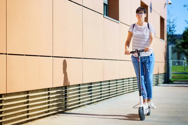 Mulher andando pela cidade em uma scooter elétrica — Fotografia de Stock