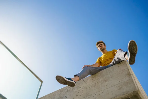 Hombre sentado en una cornisa mirando a su alrededor — Foto de Stock