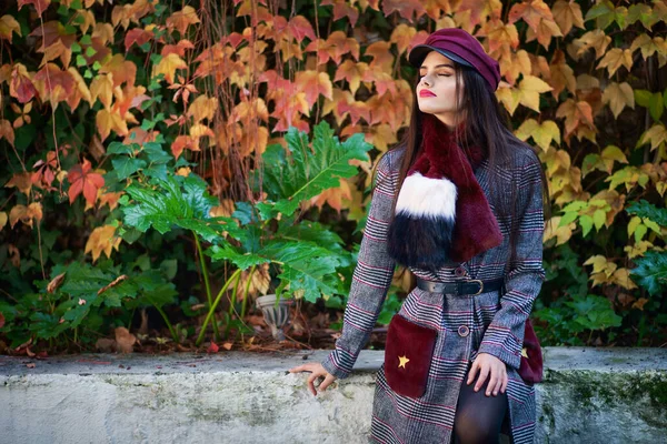 Schönes Mädchen mit sehr langen Haaren trägt Wintermantel und Mütze im Herbst Blätter Hintergrund. — Stockfoto