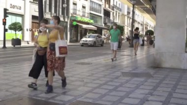 Ticari bir sokakta maske takarak yürüyen insanlar.
