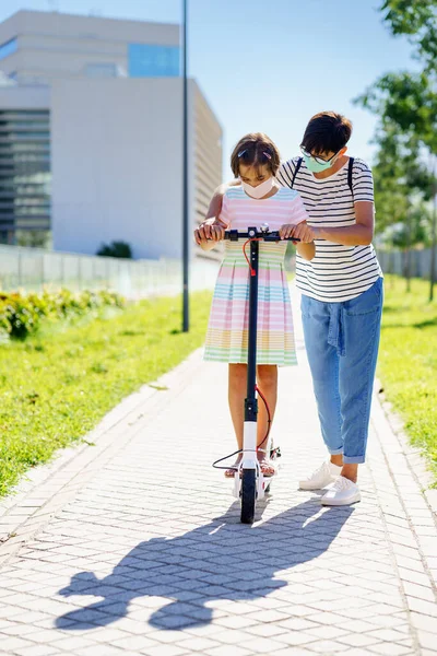 Mother teaching her daughter to ride an electric scooter — Stock Photo, Image