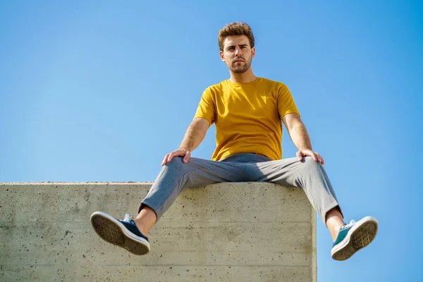 Uomo seduto su un cornicione a guardarsi intorno — Foto Stock