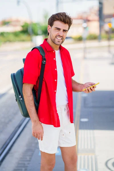 Jeune homme attendant un train dans une gare extérieure — Photo