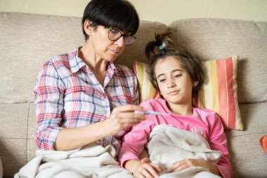 Anne kızlarının ateşini ölçmek için ateşini ölçüyor.