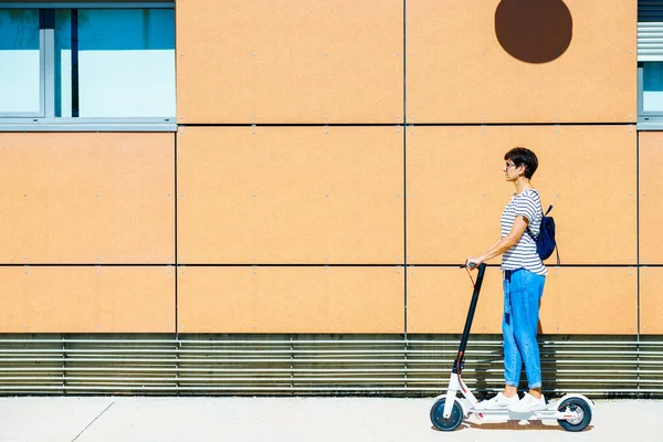 Femme chevauchant autour de la ville sur un scooter électrique — Photo