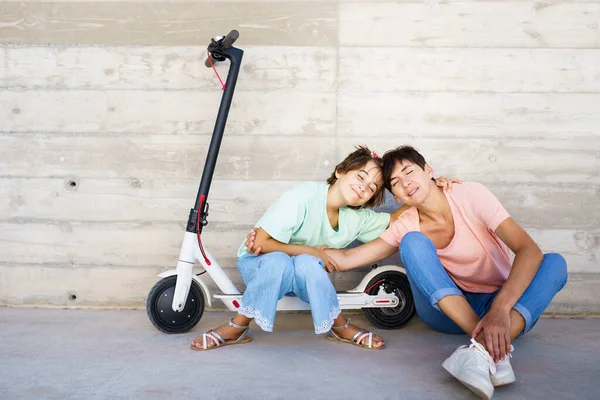 Mother and daughter sitting on an electric scooter — Stock Photo, Image