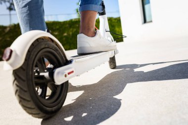 Şehirde elektrikli scooterıyla dolaşan bir kadın.