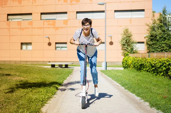 Vrouw rijdt rond in de stad op een elektrische scooter — Stockfoto