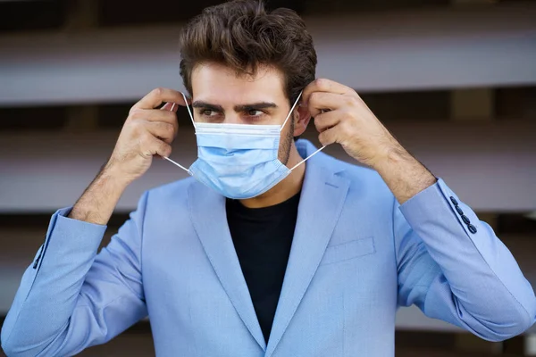 Zakenman zet een chirurgisch masker op om te beschermen tegen het coronavirus. — Stockfoto