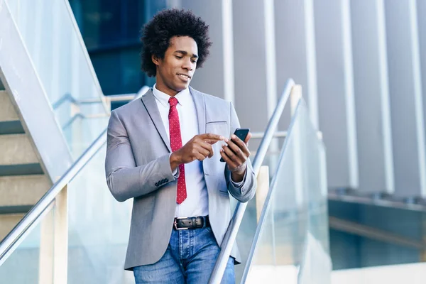 Black Businessman använder en smartphone nära en kontorsbyggnad — Stockfoto