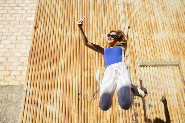 Дівчина стрибає під час створення селфі зі своїм смартфоном . — стокове фото