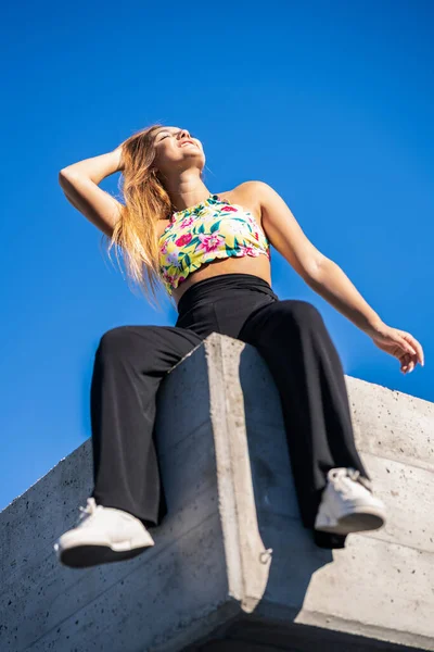 Lustiges junges Mädchen sitzt auf Stadtmauer — Stockfoto