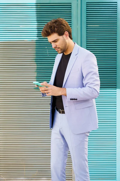 Takım elbiseli genç adam dışarıda akıllı telefonla mesajlaşıyor.. — Stok fotoğraf