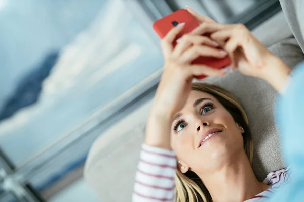 Primer plano de la mujer usando su teléfono inteligente acostado en el sofá. —  Fotos de Stock