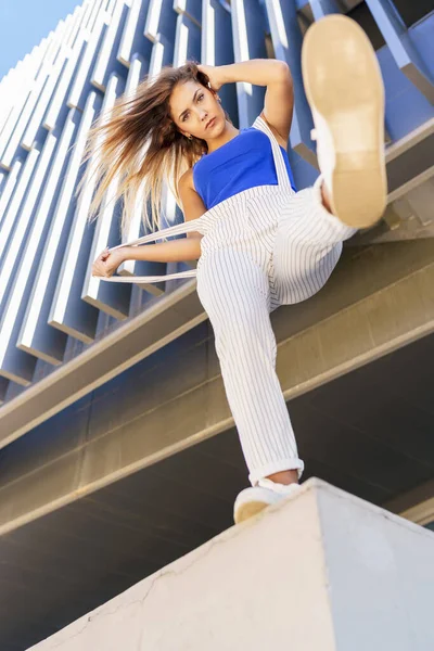 Blick von unten auf ein junges Mädchen, das ihren Fuß in die Luft wirft. — Stockfoto