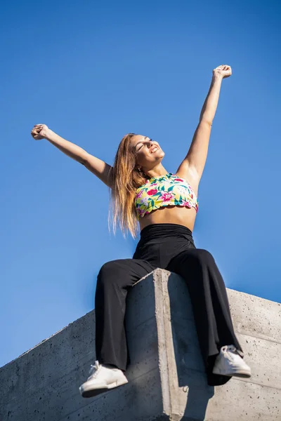 Jonge vrouw opent armen tegen blauwe lucht — Stockfoto