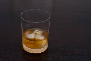 Viski, viski, viski ya da koyu ahşap bir masa üzerinde zarif bir bardak buzlu rom