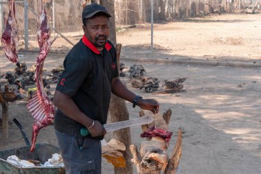 Traditional Market Scene in Opuwo Man Butchering Meat clipart