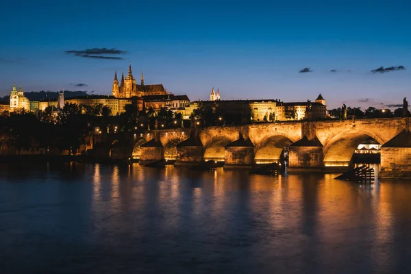 プラハのカレル橋聖ヴィート大聖堂とプラハ城の街並とヴルタヴァ川を隔てて夜 — ストック写真