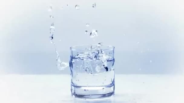 Eiswürfel spritzt in Zeitlupe in Wasserglas