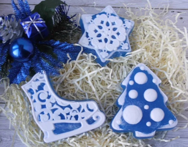 El yapımı sabun Noel ağaçları, paten ve kar taneleri ve hafif bir arka plan üzerinde mavi Noel süsleri şeklinde. Noel top, hediye ve kozalaklı şube. Mutlu Noeller ve mutlu yeni yıl!