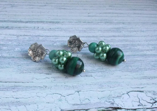 Malaita ve hematit hafif bir arka plan üzerinde yapılmış el yapımı küpe.