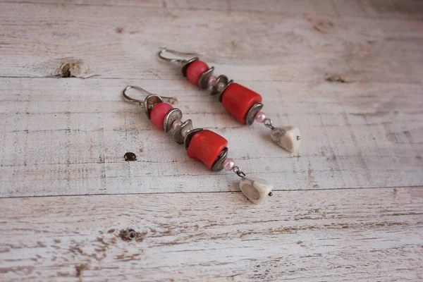 Beyaz el yapımı küpe ve pembe mercan hafif bir arka plan üzerinde.